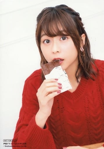 Minase Inori in a red crochet top, biting into a chocolate bar and looking back
