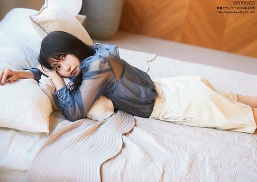 Amamiya Sora wearing a dark blue blouse, translucent sleeve top and white skirt, lying down on a bed leaning onto a pillow and looking back