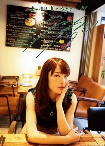 Komatsu Mikako in a dark green top, with her hand against her left side jaw, in a café