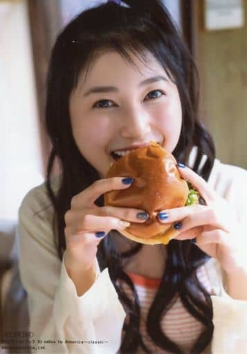 Amamiya Sora dressed in red and white striped camisole below a thin pajama blouse, holding on to a burger